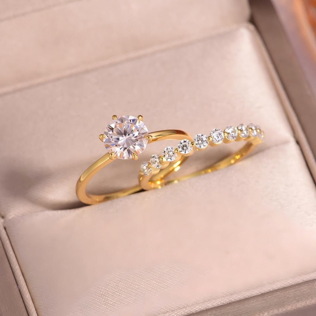 Angled shot of gold round moissanite crown solitaire and bubble band stacking set in box.