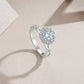 Side view of round cut moissanite floral halo ring on display.