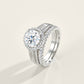 Round cut moissanite halo ring with matching pave band resting on light surface.