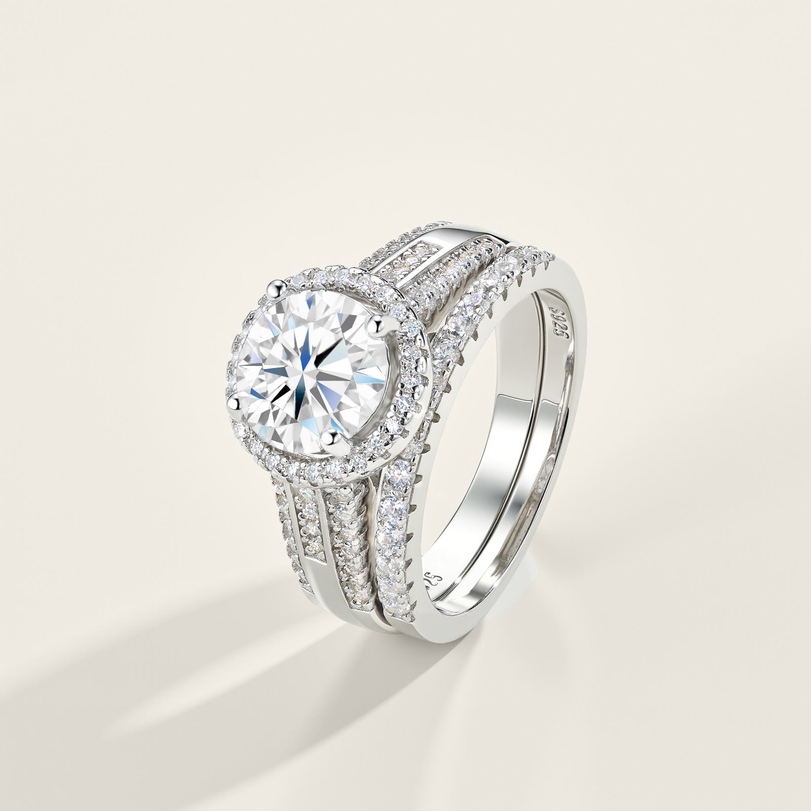 Round cut moissanite halo ring with matching pave band resting on light surface.
