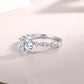 Round cut moissanite leaf station ring resting on light surface.