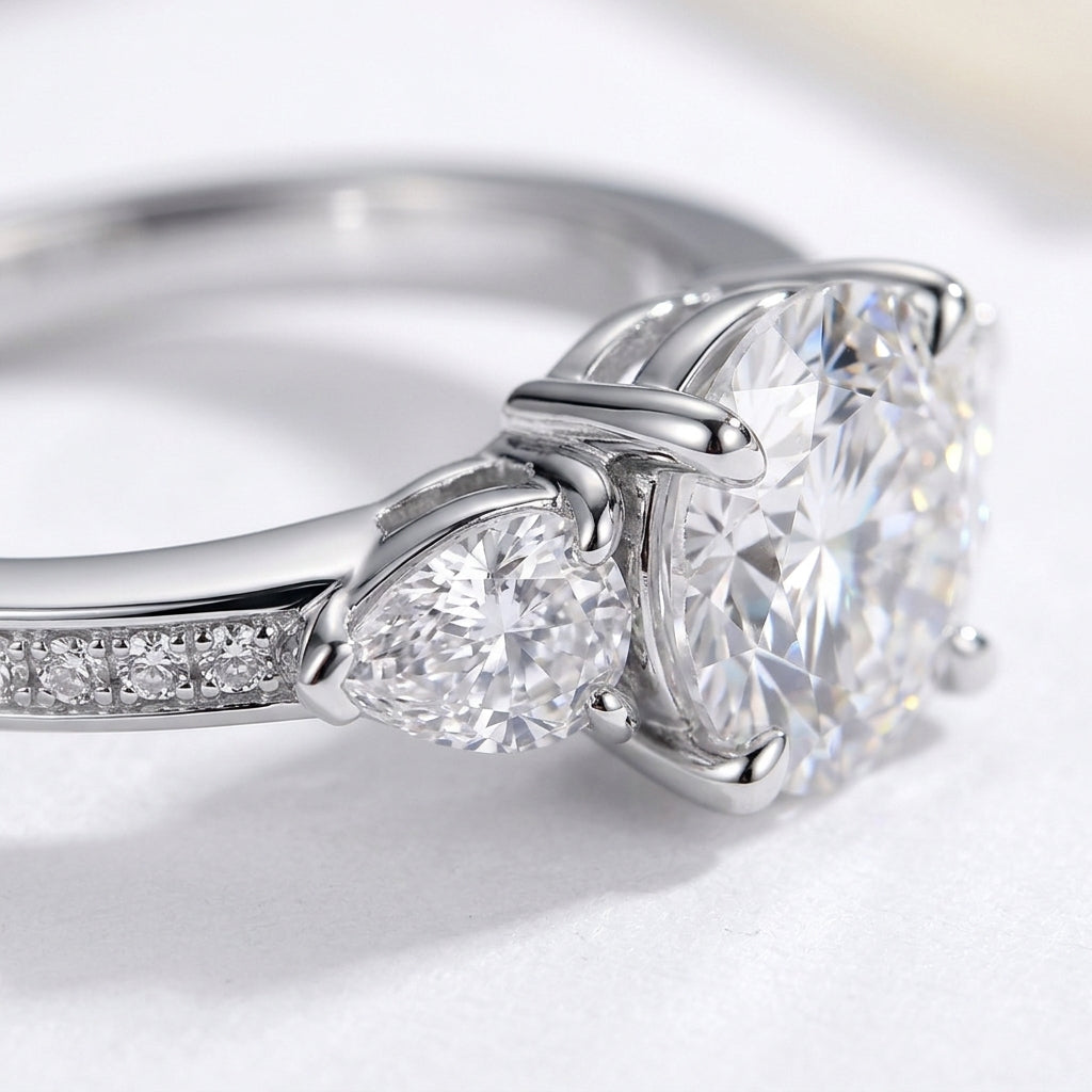 Macro view showing 4-prong basket setting and pear side stones on moissanite ring.