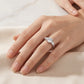 Model showing round cut moissanite three stone engagement ring on hand in soft light.