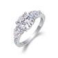 Round moissanite three stone ring with pear cut side gems standing on display.