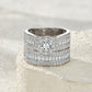 Classic silver round moissanite wide bridal set resting on a soft textured background.