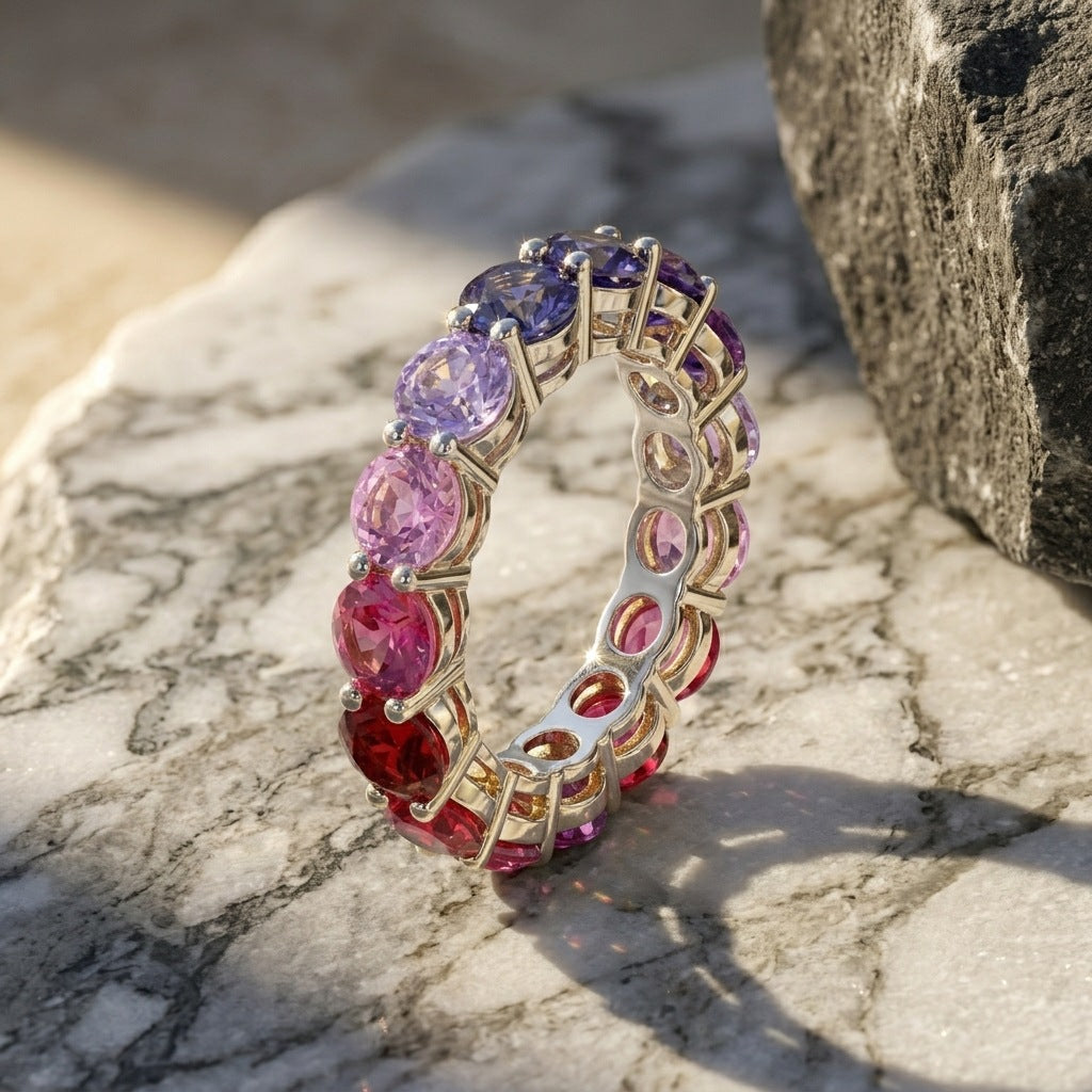 Gold round rainbow gradient moissanite eternity band ring standing on white marble slab