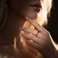 Model wearing gold round rainbow gradient moissanite eternity band ring on hand