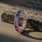 Silver round rainbow gradient moissanite eternity band ring displayed on dark slate stone
