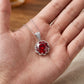 Red gemstone pendant on a silver chain held in a hand