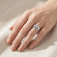 Model wearing round cut three-stone engagement ring stacked with curved guard band.