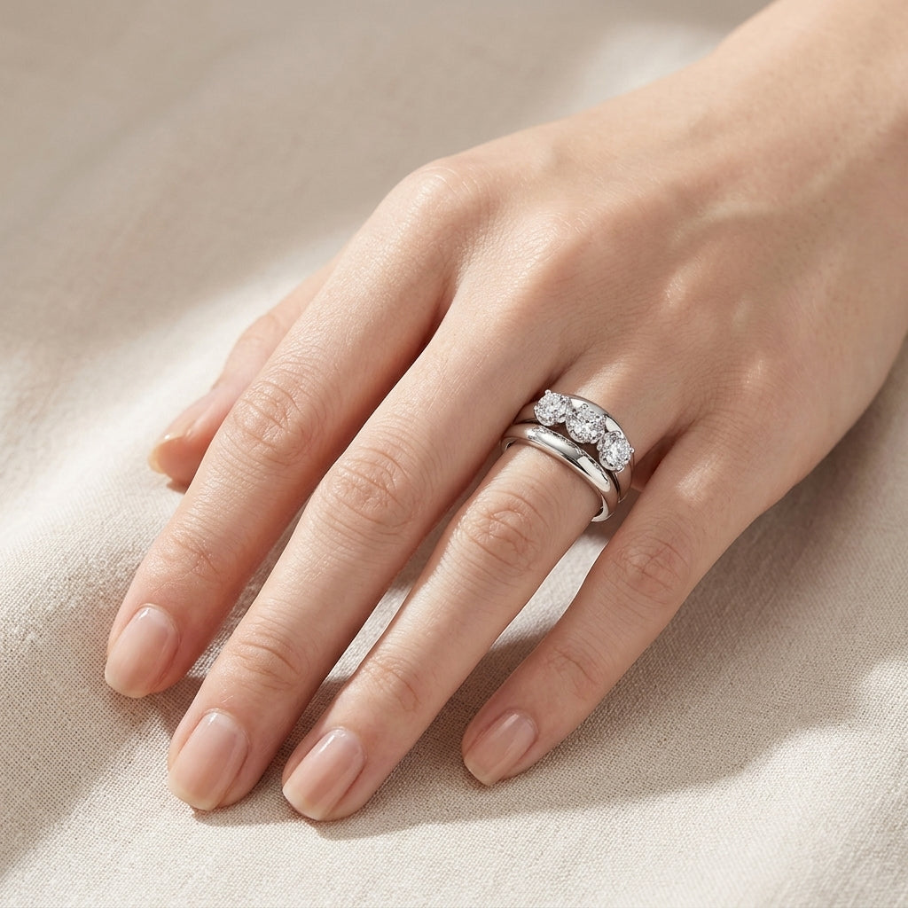 Model wearing round cut three-stone engagement ring stacked with curved guard band.