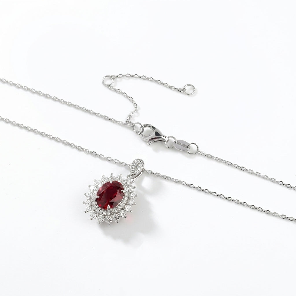 Silver necklace with a red gemstone pendant on a white background