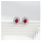 Pair of earrings with red gemstones and diamond-like accents on a white background