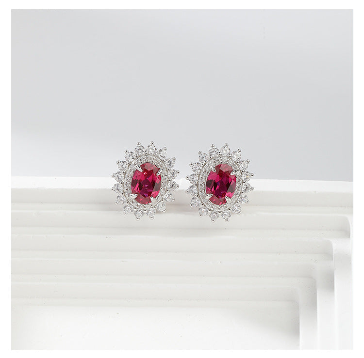 Pair of earrings with red gemstones and diamond-like accents on a white background