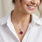 Woman wearing a silver necklace with a red pendant