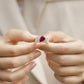 Close-up held in hands, luxury 2-piece pear-cut ruby stackable statement ring under soft lighting.