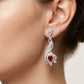 Close-up of a woman wearing a silver earring with a red gemstone.