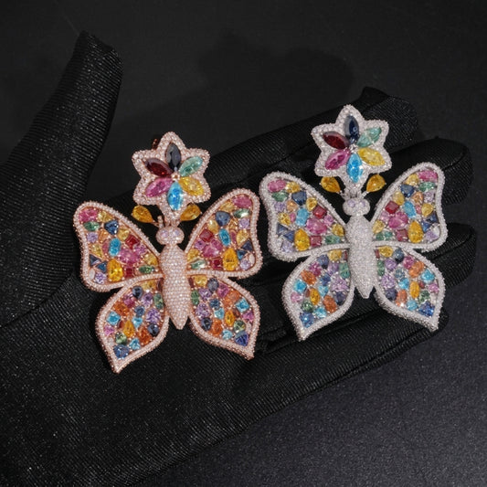 Hand in black glove holding rose gold and silver S925 multi-color moissanite butterfly pendants