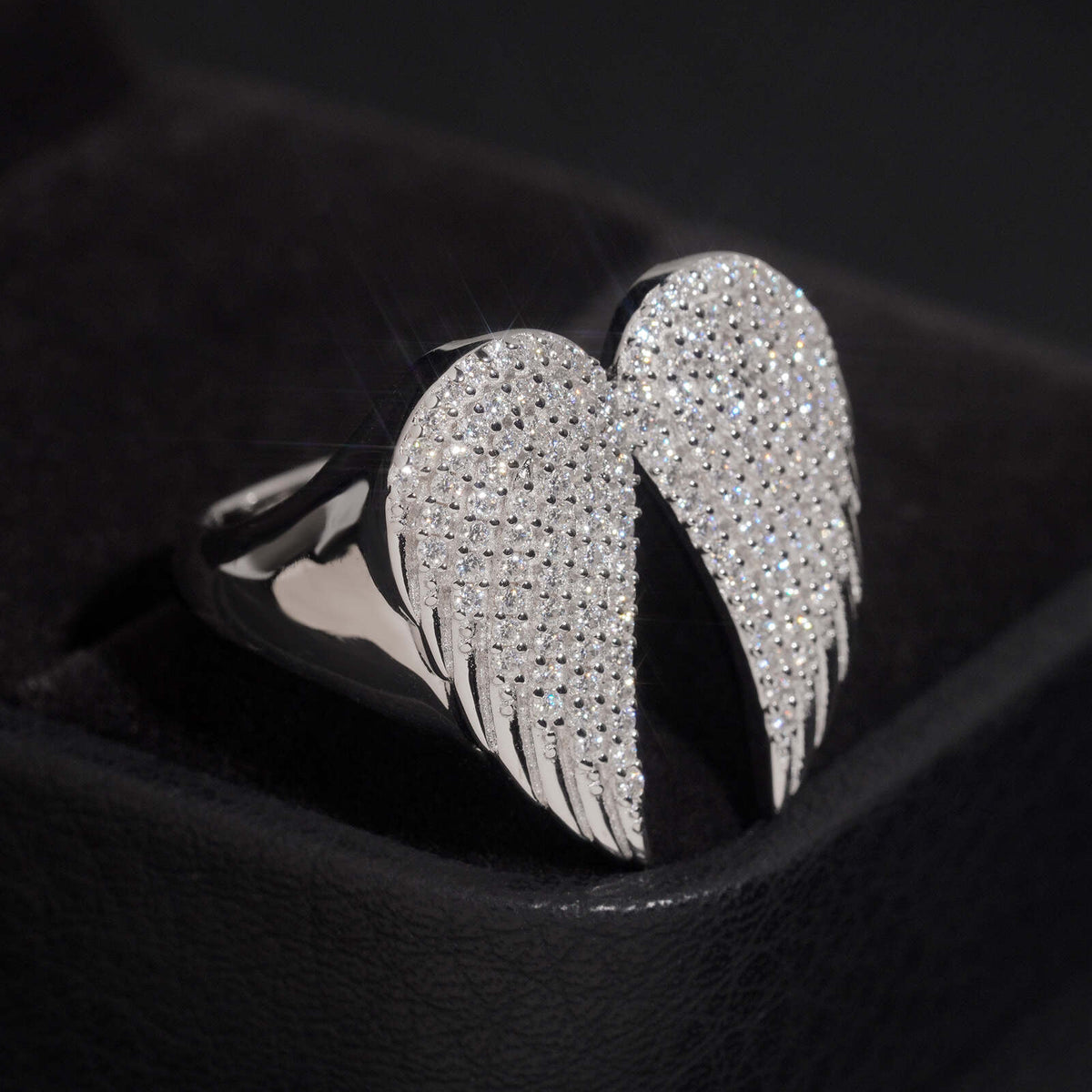 Side angle view of S925 silver iced out moissanite angel wings ring on display stand