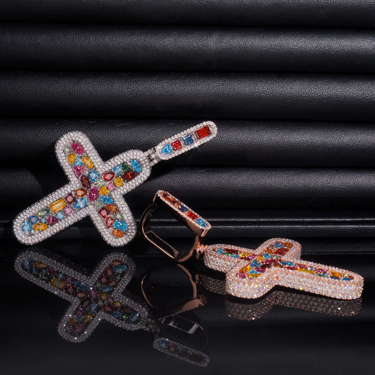 Multi-color moissanite rounded cross pendants in silver and rose gold with long bail on dark surface