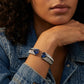 Woman wearing a silver bracelet with blue gemstones against a denim jacket.