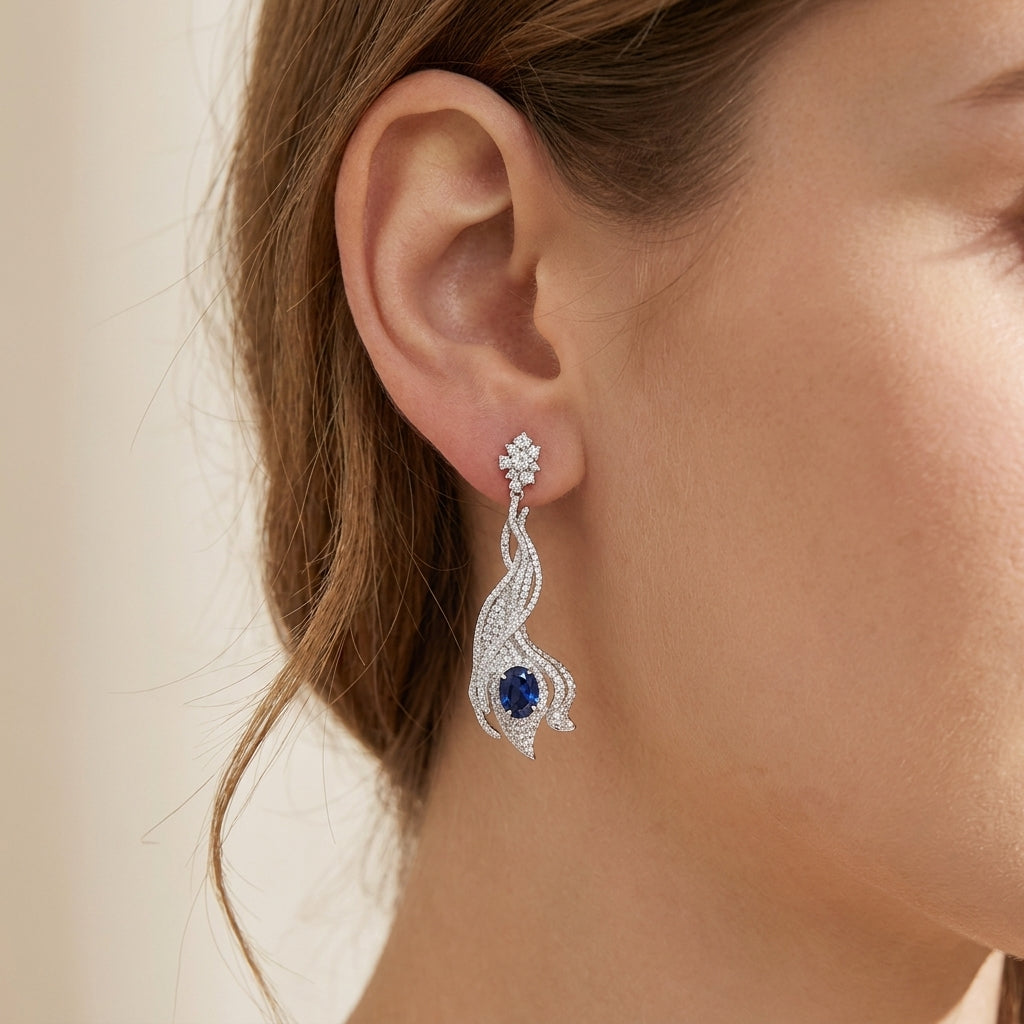 Model wearing 5ct blue sapphire wave earrings, side profile, elegant hair styling.