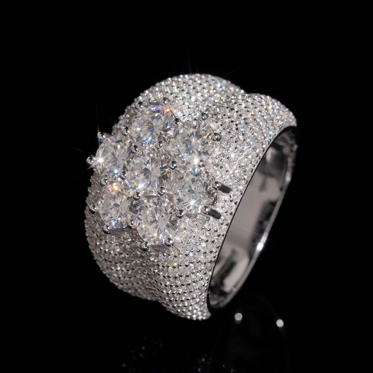 Angled view showing floral cluster setting of seven stone moissanite wide ring on dark background