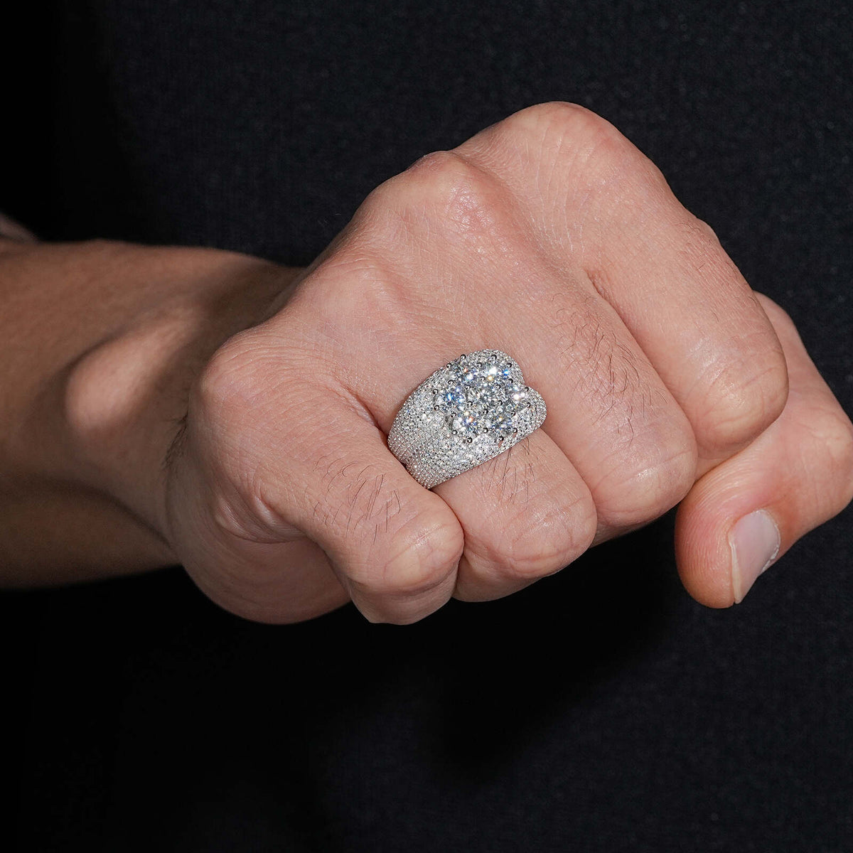 Person wearing seven stone flower cluster moissanite wide band ring on finger