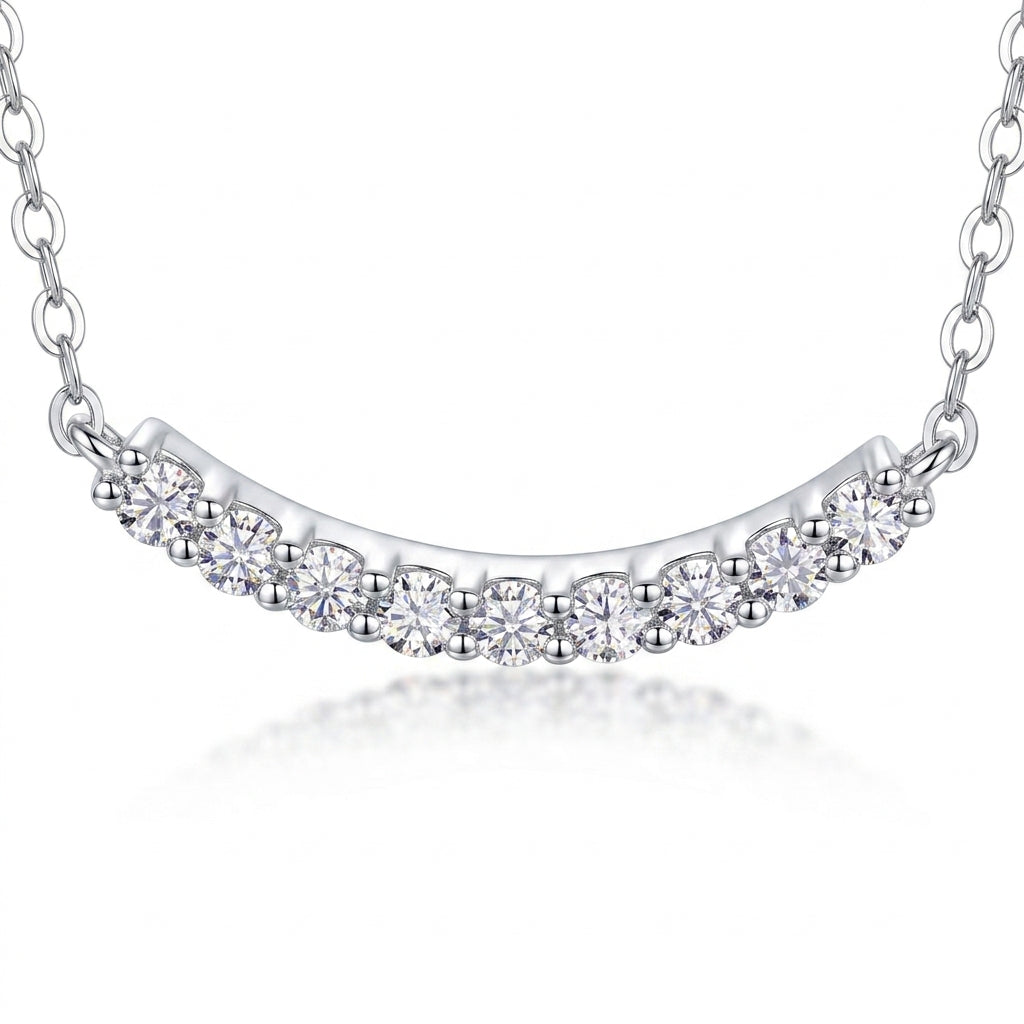 Close-up view of shared prong setting on uniform moissanite curved smile bar pendant.