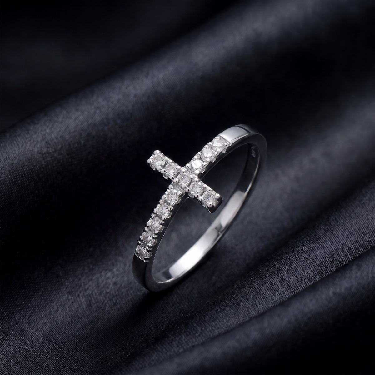 Side profile view of sideways cross lab grown diamond ring standing on black silk   