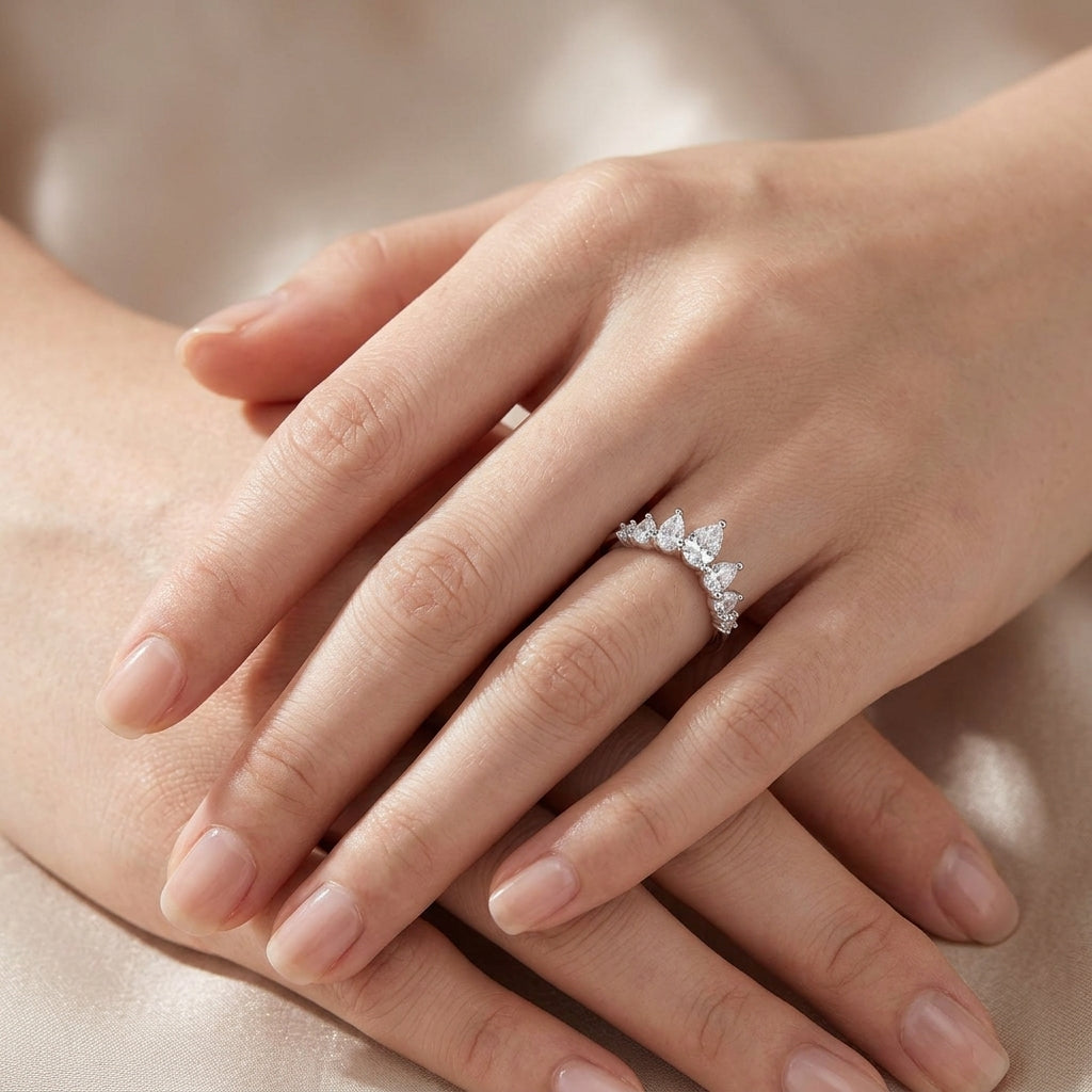 Close-up view of a model wearing silver pear cut moissanite tiara crown stacking ring on hand.