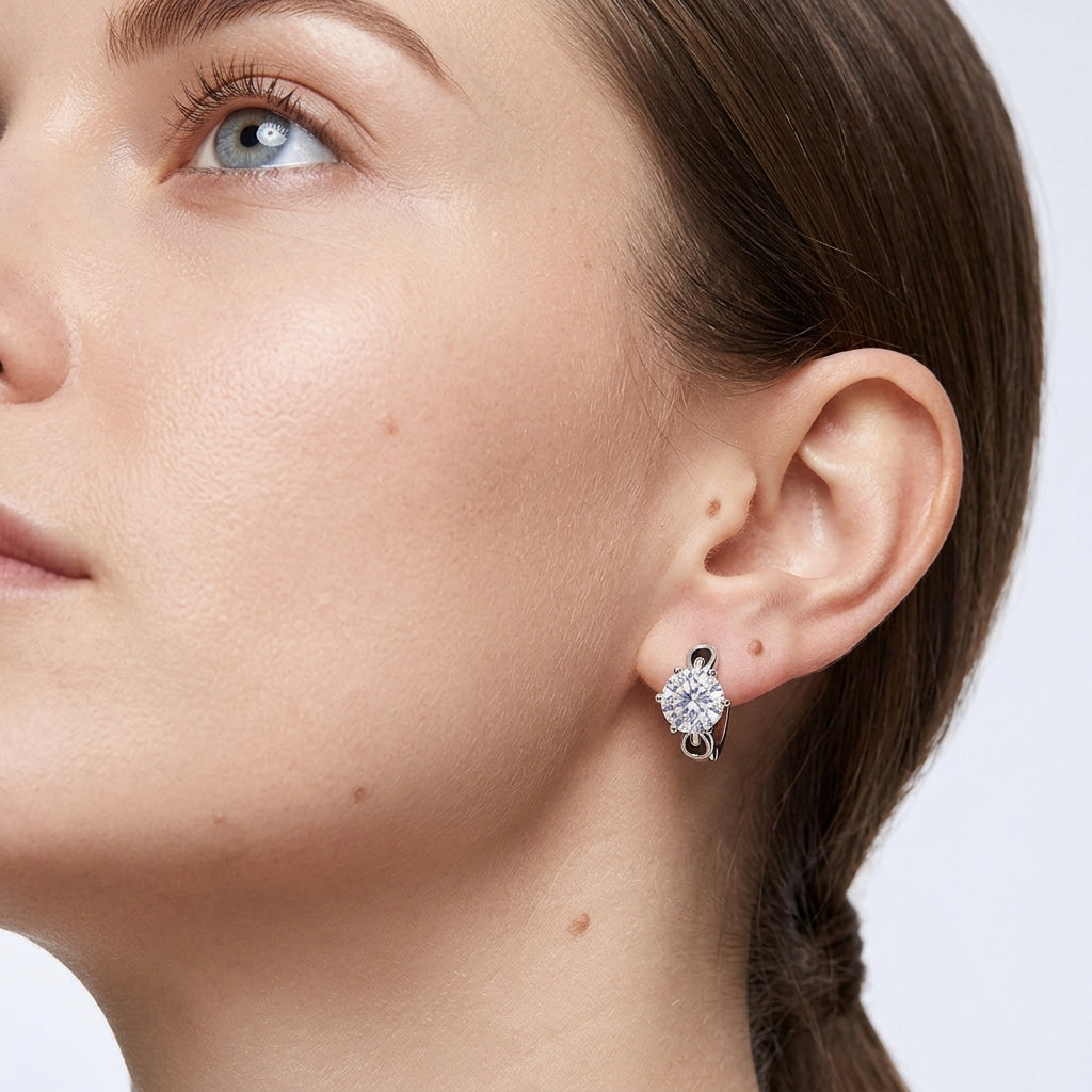Close-up profile of model wearing round diamond six-prong solitaire huggie hoop earrings.