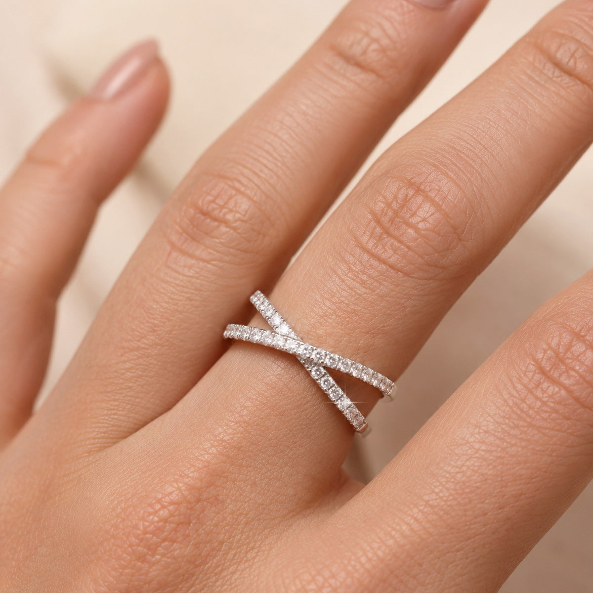 Woman wearing sparkling lab grown diamond criss cross x-ring on index finger