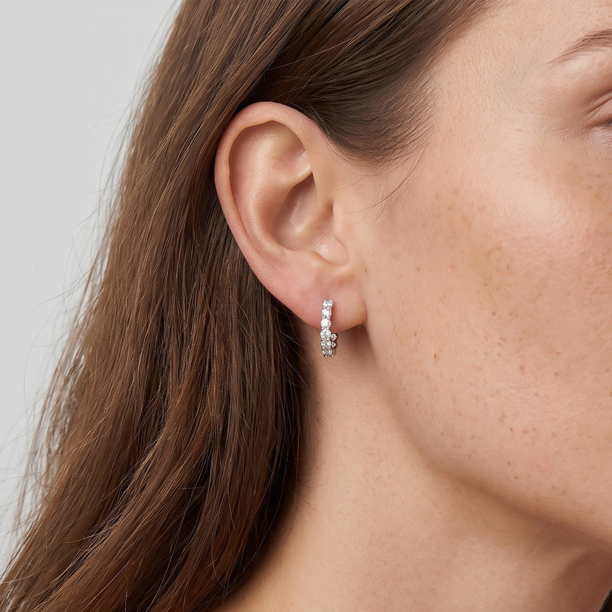 Model wearing small sparkling lab grown diamond eternity hoop earrings