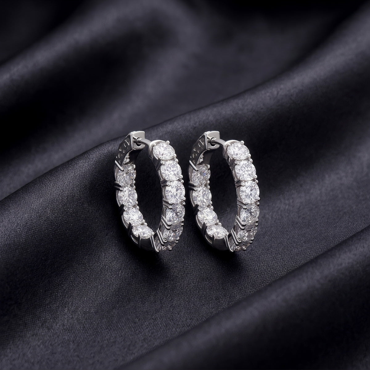 Sparkling lab grown diamond eternity hoop earrings set on dark black silk fabric