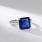 Side profile view of a square-cut blue sapphire solitaire statement ring resting on a sleek surface with soft shadows.