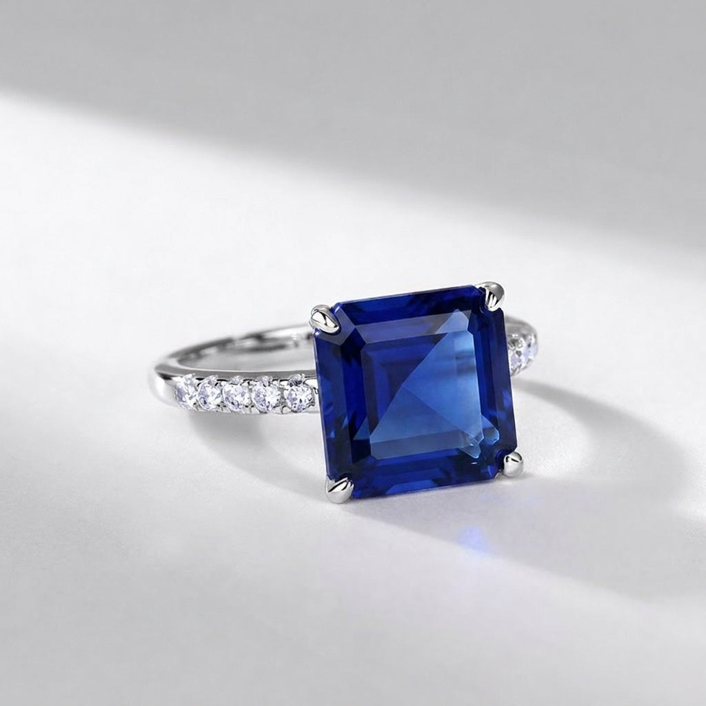 Side profile view of a square-cut blue sapphire solitaire statement ring resting on a sleek surface with soft shadows.