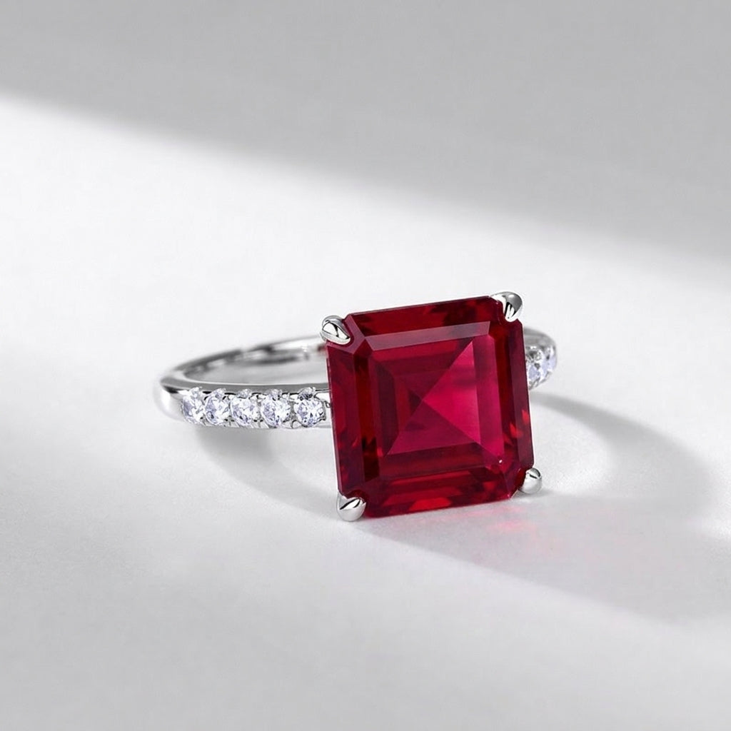 High-angle view of a luxury minimalist square ruby cocktail ring styled on a woman's finger.