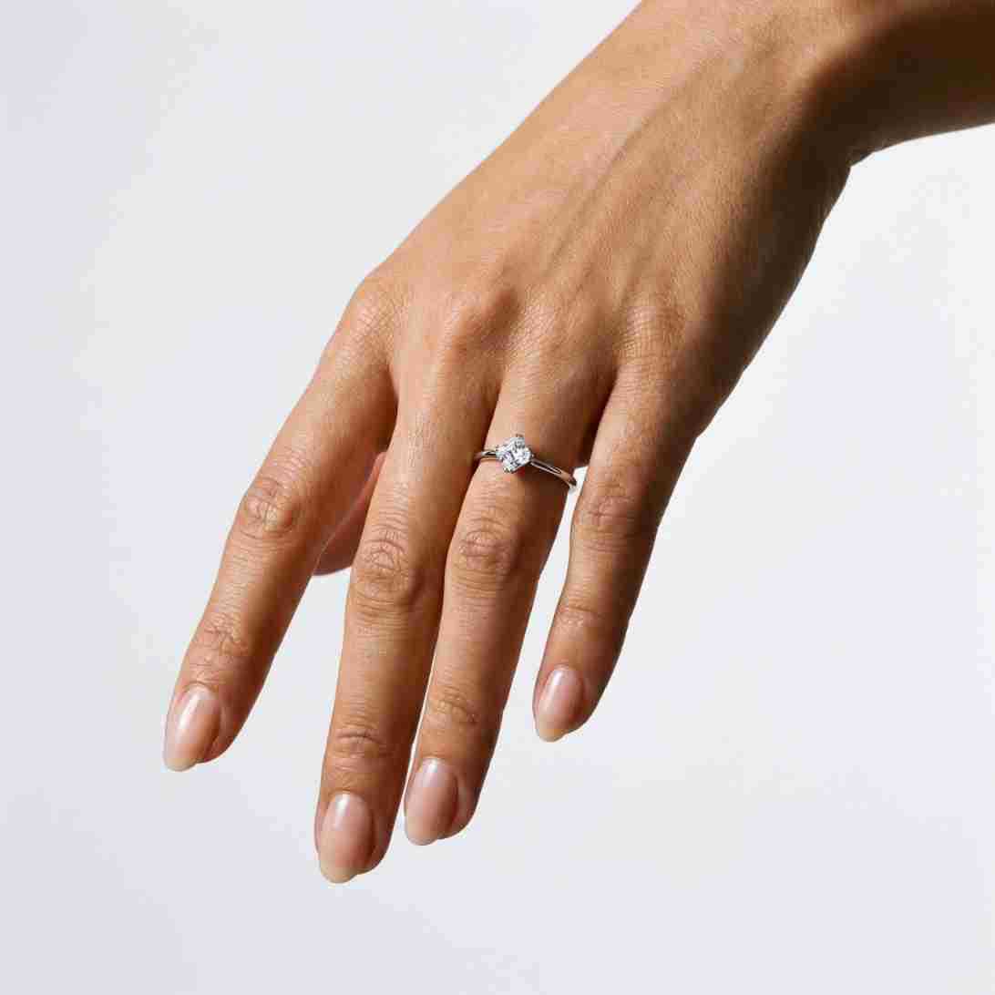 Full hand view of model wearing square emerald cut kite set engagement ring.