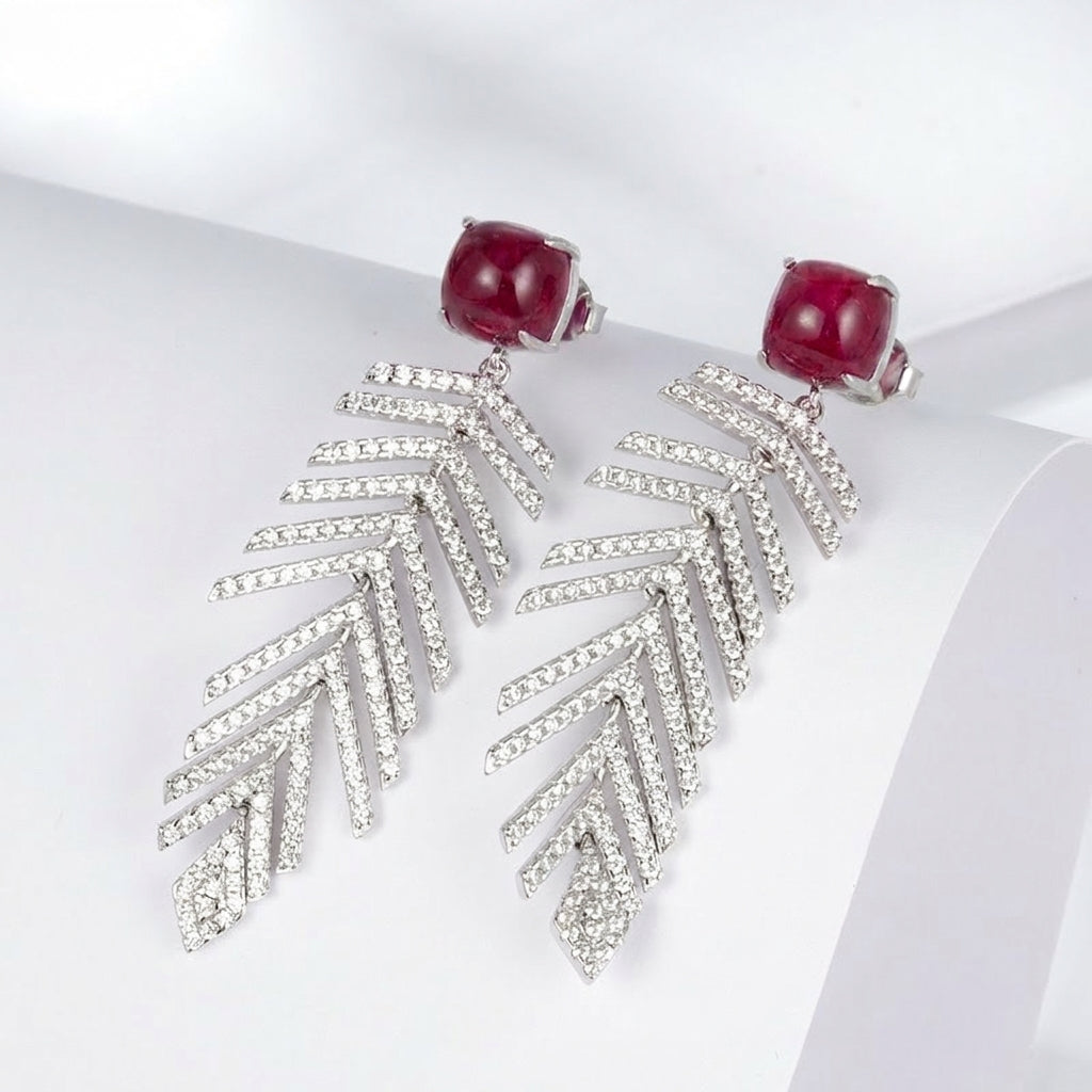 High-angle perspective view of a pair of handcrafted lab-grown ruby wheat chandelier earrings with crisp shadows.
