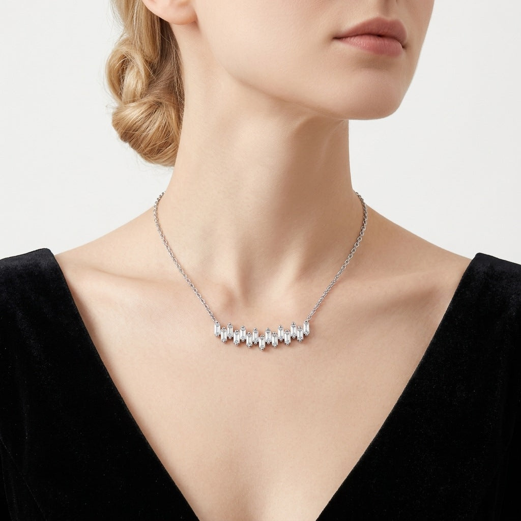Model wearing staggered baguette moissanite bar necklace on collarbone.