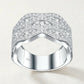 Studio front display of sterling silver wide wave pave moissanite crossover statement ring showing symmetric fluid curves.