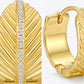 Detailed close-up of gold textured leaf huggie hoops showing the pavé moissanite spine and S925 stamp.