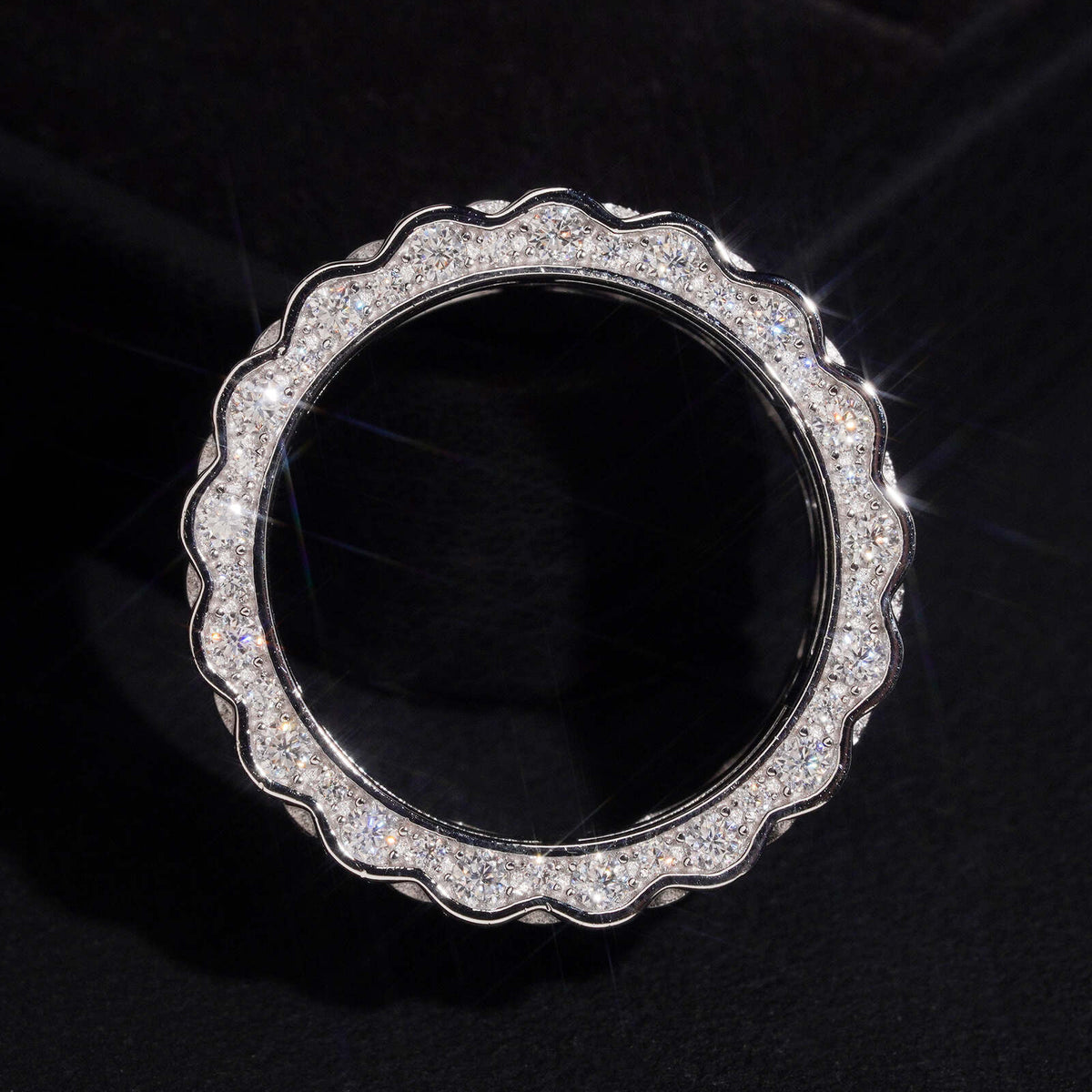 Front view of three row watch link moissanite wide band ring on dark background