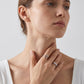 Lifestyle shot of model showcasing round three-stone engagement ring and curved guard band set.