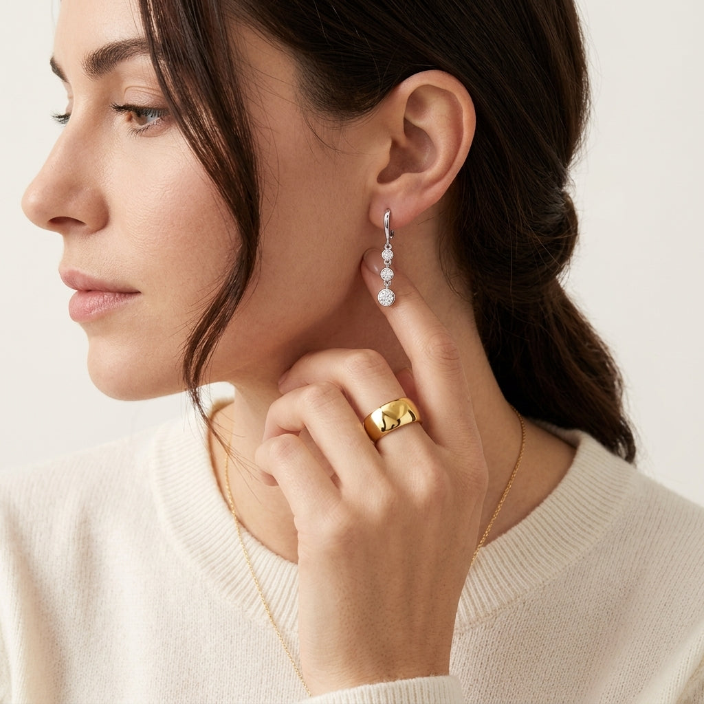 Model wearing graduated three stone bezel set moissanite linear drop earrings.