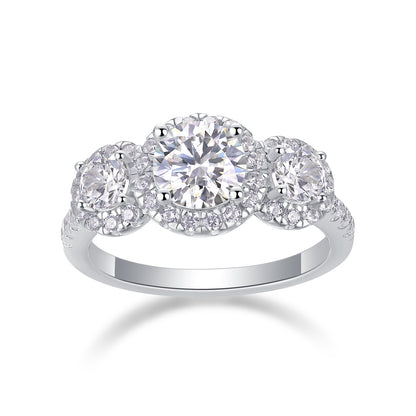 Three stone halo moissanite engagement ring with pave band on white background.