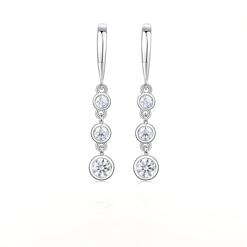 Three stone moissanite drop earrings with graduated bezel set linear dangle on white background.