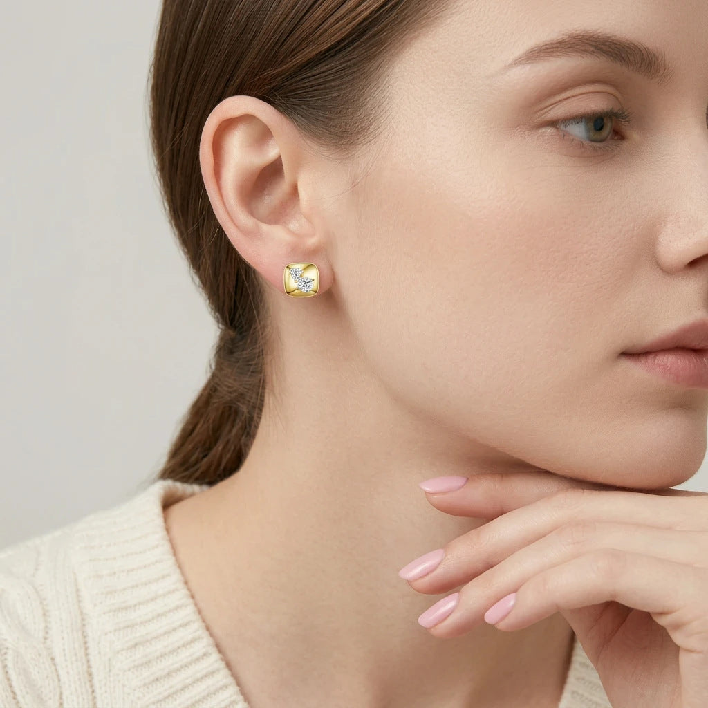 Editorial fashion lookbook portrait of a model styling timeless gold chunky cushion square moissanite stud earrings near her chin.
