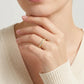 High-end fashion lookbook view of a model wearing a timeless romantic gold bezel moissanite anniversary jewelry piece with a cozy knit sweater.